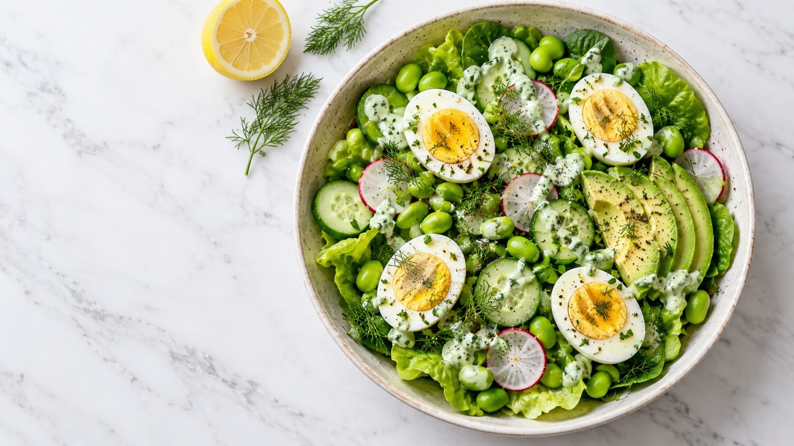 Halved hard-boiled eggs, edamame, cucumber, radishes and avocado over butter lettuce and spinach with green herb dressing.