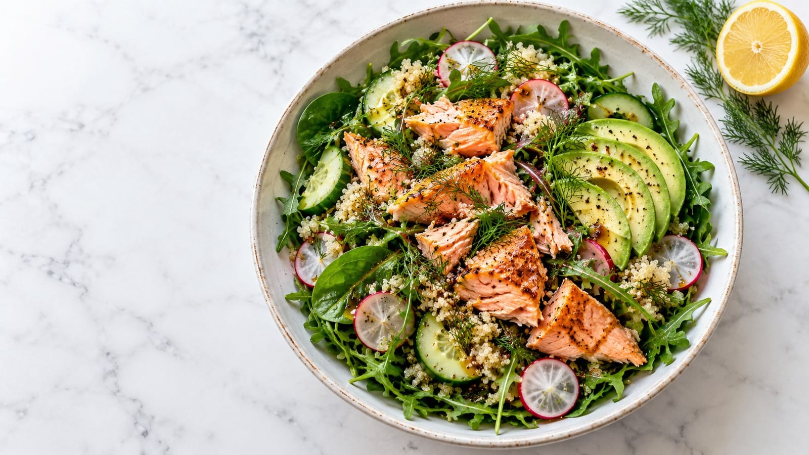 Flaked roasted salmon with arugula, spinach, quinoa, cucumber, radishes, avocado and dill in a ceramic salad bowl.